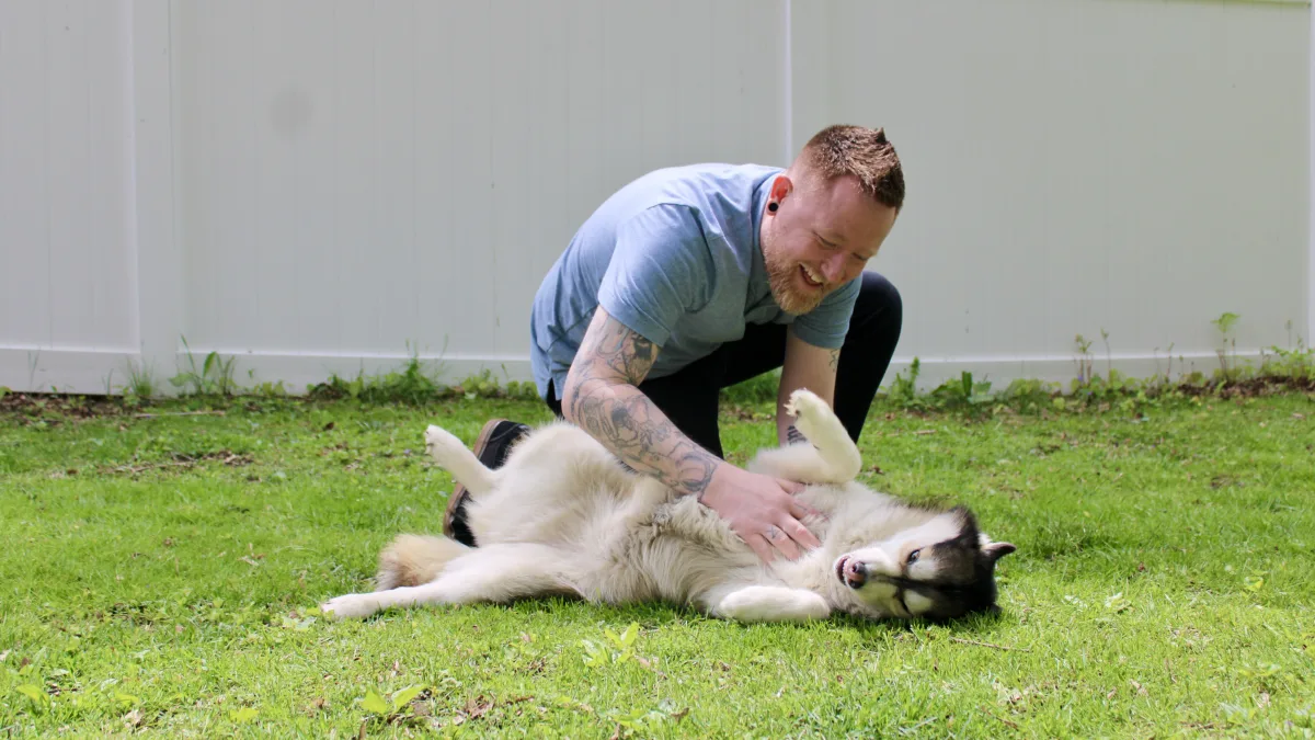 Andrew playing with Misha the husky in the yard